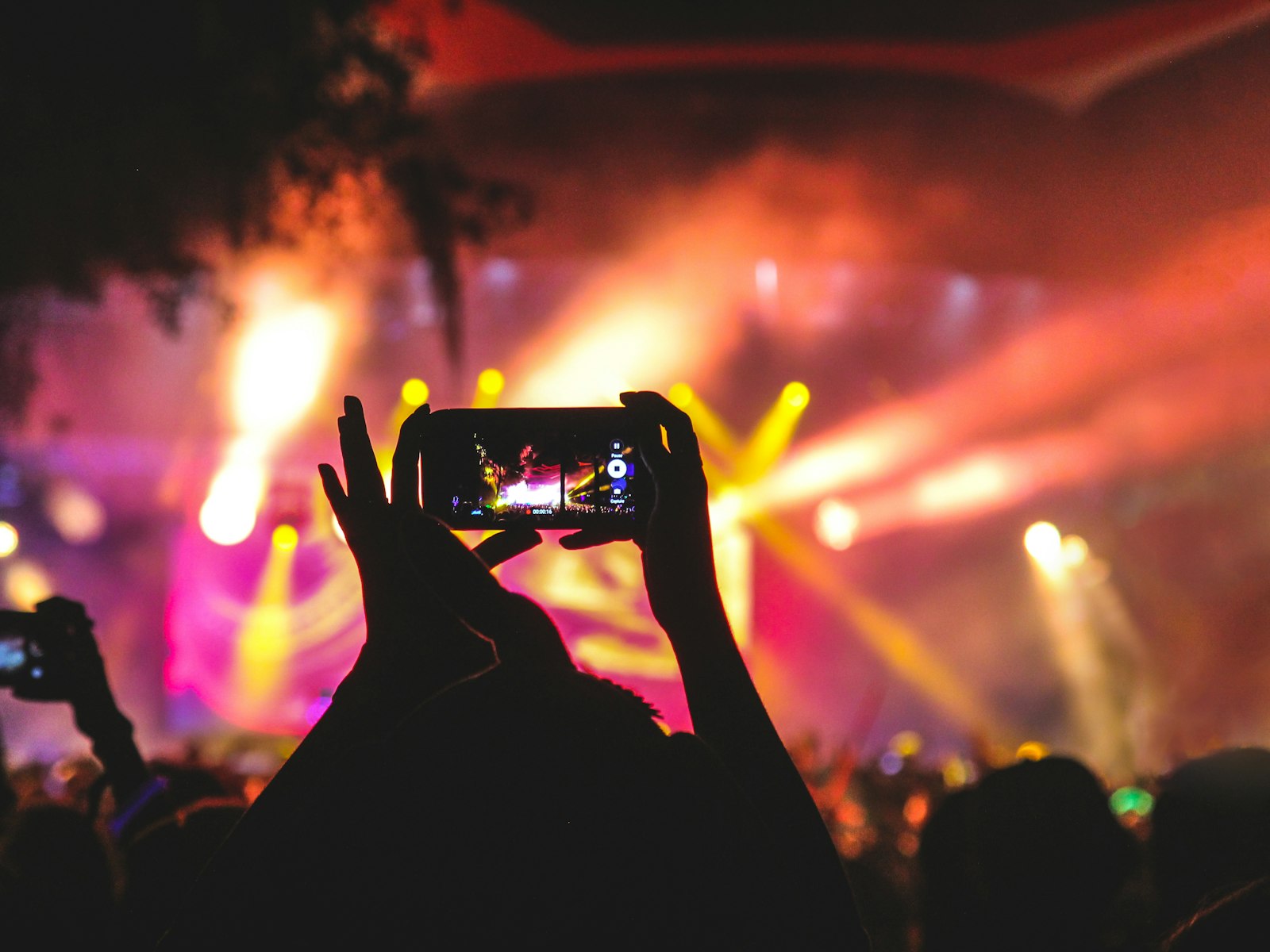 A worshipper filming the stage on their phone during a night of worship
