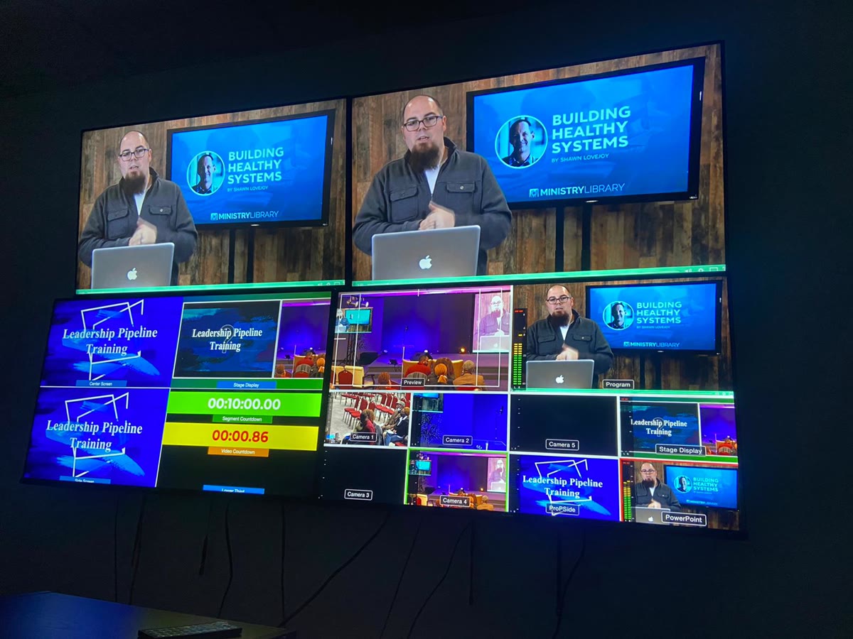 The Living Spring production booth: a wall of screens showing camera feeds, ProPresenter outputs, the stage display and countdowns
